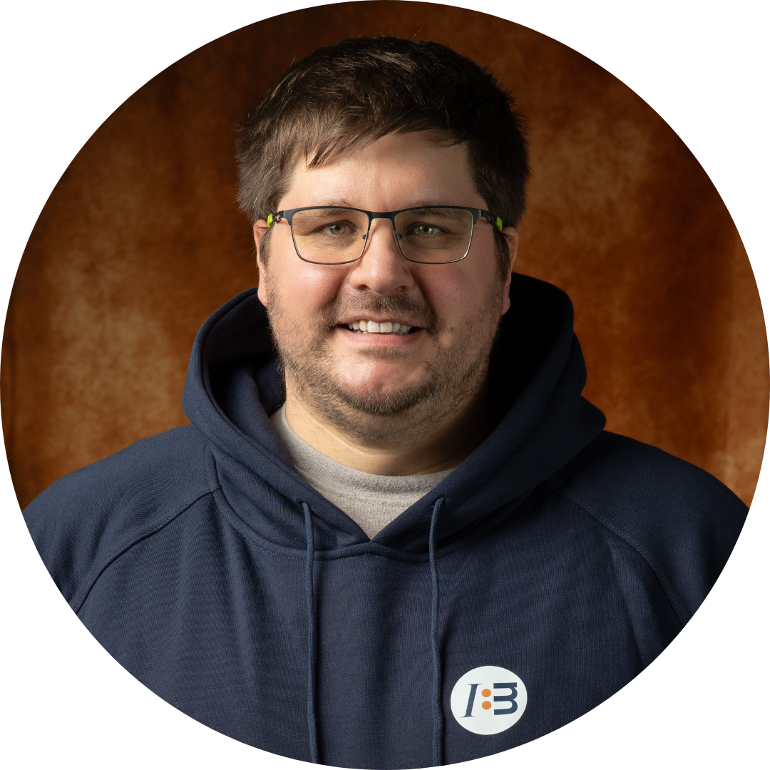 Mann mit Brille im Hoodie vor braunem Hintergrund.